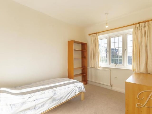 Here is the third bedroom, with space for drawers and shelves. There is a carpeted floor and a window facing the front of the house.