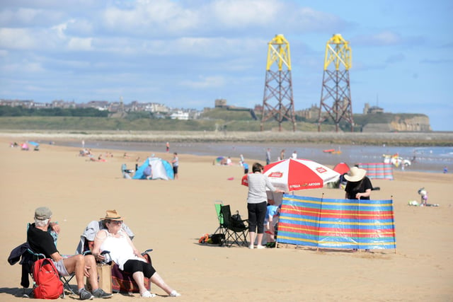 People sit in the sun and enjoy the warm weather at Sandhaven beach.