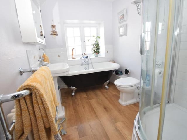 The main bathroom at the £350,000-plus cottage is fitted with a traditional-style suite, complete with luxury roll-top bath with mixer tap and shower handset. The bespoke feel continues with a separate shower cubicle. There is also a pedestal wash hand basin and WC with high-level cistern.