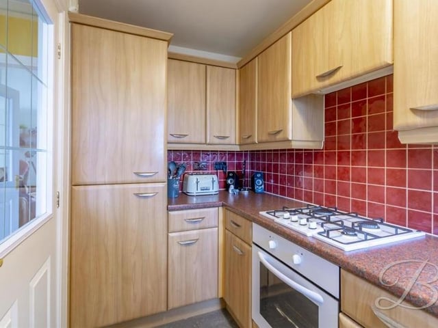 Our second photo of the kitchen shows that its integrated appliances include a fridge freezer. A window overlooks the front of the property, while the pictured door leads back into the entrance hallway.