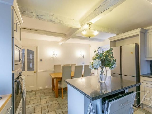 The kitchen includes a smart central island with an integrated dishwasher installed. The tiled floor is attractive too.