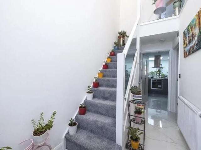The entrance hall features a glass balustrade staircase leading to the first floor of the £300,000 dormer bungalow. Under the stairs is a pantry cupboard.