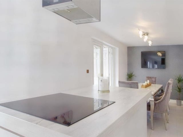 This is our first look at the contemporary and open-plan kitchen/dining room. An induction hob is set within the central island beneath an extractor hood.