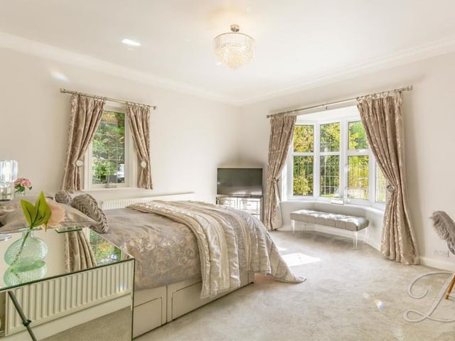 The master bedroom at the £795,000 house is sublime, with its lovely bay window and a walkway that leads to a sleek fitted wardrobe and modern en suite bathroom. The floor is carpeted.