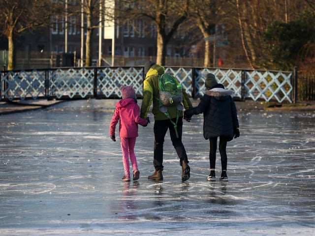 People walk on a frozen pond at Victoria Park