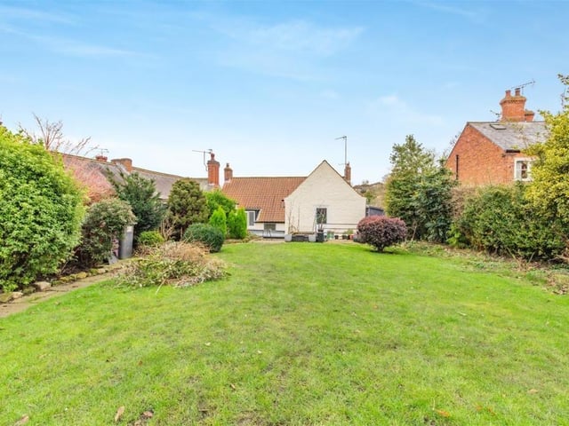 This is what the property looks like from the back, stretching down the lengthy lawn, with its well-stocked borders.