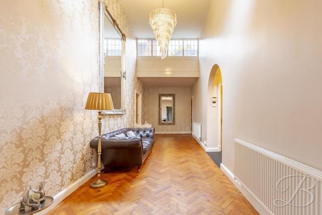Another shot of the grand hallway as it extends into the heart of the house. It boasts classic parquet flooring, neutral decor and a wealth of natural light.