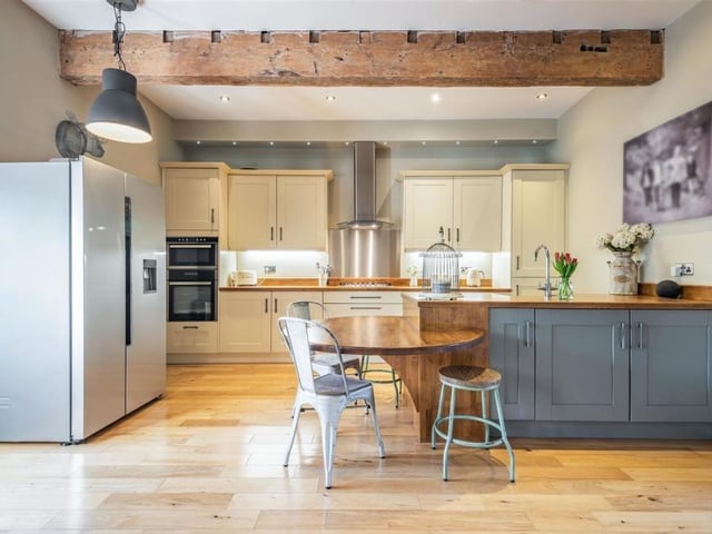 Let's move into the superb, open-plan kitchen/diner now. Marvel at its feature beamed ceiling and range of contrasting cream and grey cabinets, comprising wall cupboards with under-lighting, base units and drawers with wood worktops above. Integrated appliances include a fridge freezer.