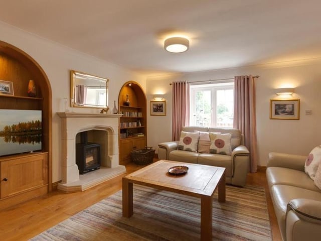The focal point of the sitting room is a feature wall, which incorporates a Stovax log-burning stove, with a stone mantle, surround and hearth. There are also two inset oak storage units with recessed light points, open shelving and cupboards.