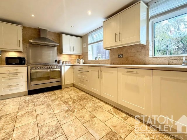 This modern, traditional-style kitchen features a range of integrated appliances, an attractive selection of base and wall units, and space for a freestanding fridge freezer.