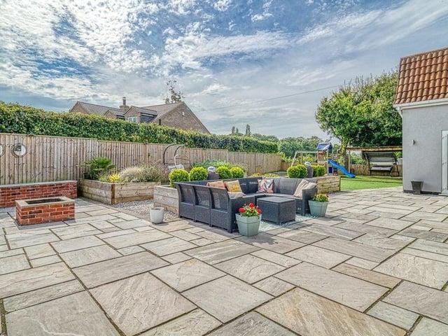 Tim to step outside now to marvel at the property's glorious and private garden. The Indian sandstone patio has a seating area, with flowerbeds made from sleepers.
