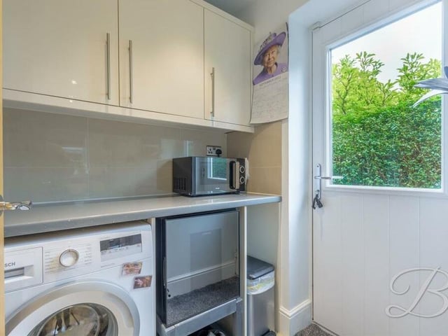 Just off the kitchen is a small utility room, complete with a range of high-gloss units, and space and plumbing for a washing machine. A door leads outside.