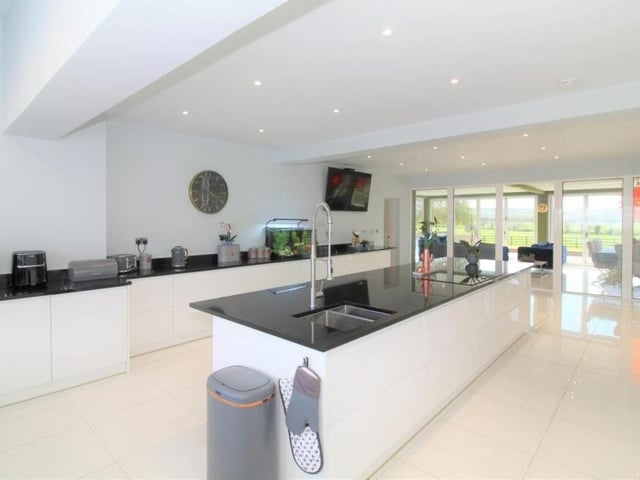 The shiny and sparkling kitchen from a different angle. The glass doors at the end lead into the sun room or garden room.