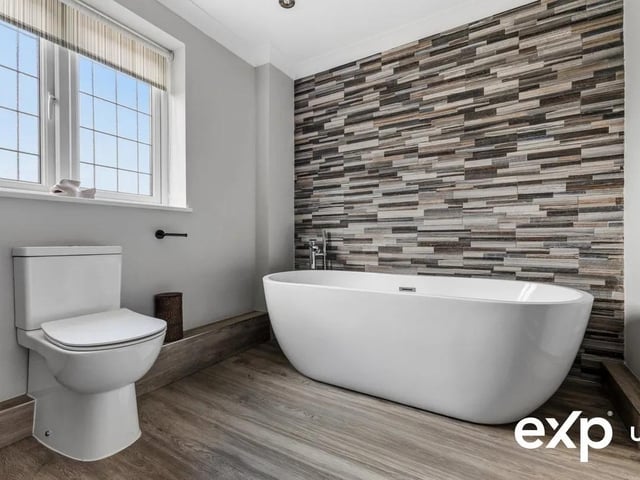 The family bathroom is fitted with a suite comprising an egg-shaped bath with shower fitting, a separate shower cubicle, a washbasin in a sleek vanity unit, and a low-flush WC.