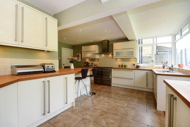 The kitchen features cream high gloss units complemented by bamboo wood worktops. It contains a Stoves range cooker, an integrated dishwasher, downlighters, a breakfast bar and doors leading to the garage and rear garden.