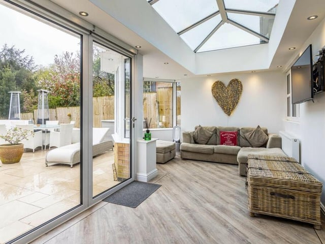 Attached to the kitchen is this modern orangery, which is bathed in natural light and overlooks the verdant garden and woodland beyond,
