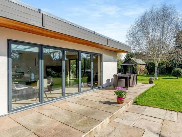 This photo shows how the stunning open-plan dining/living kitchen extension at the £690,000 property opens out on to the patio via large bi-fold doors.