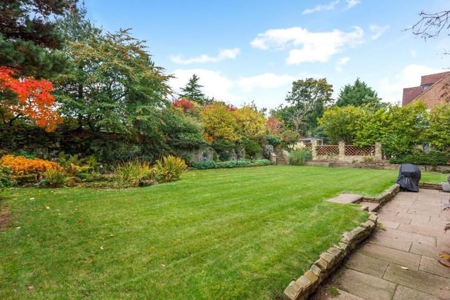 Let's take a quick look outside before we leave the £1.25 million Mansfield stunner. The rear garden is mainly laid to lawn, with with a pond, lighting and established tree-lined borders. Stone steps lead to an elevated patio area.