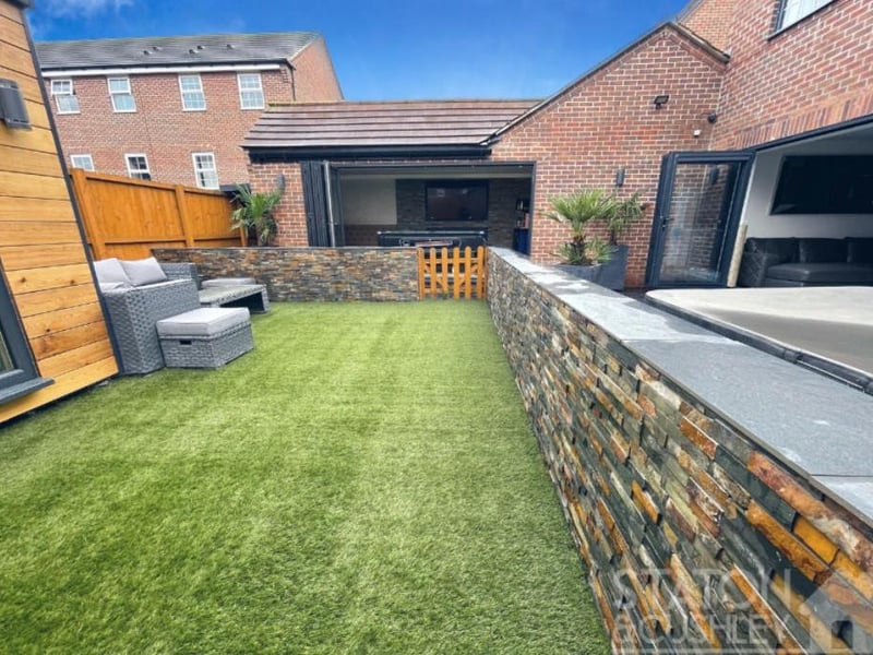 The back garden features a lawn and a seating area.