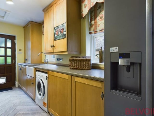 Our tour of the ground floor is completed by a galley-style utility room, with wall units providing more storage. It features a Belfast sink with mixer taps, a cupboard housing the boiler, space for a washing machine and additional fridge freezer, and a tiled herringbone floor.