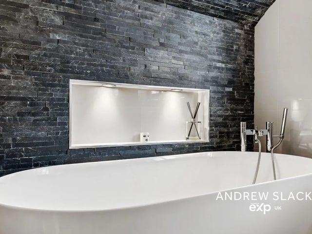 The hotel-inspired family bathroom is impressive with a freestanding tub against a dramatic slate feature wall.