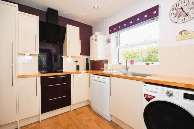 The busy kitchen is fitted with matching wall and base units, and solid work surfaces incorporating a stainless steel sink and drainer with mixer tap. Integrated appliances include a fridge/freezer and an electric hob with glass splashback.
