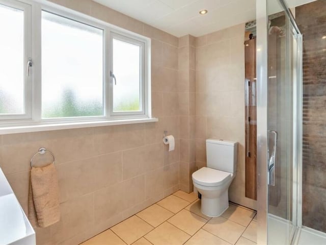 All four bedrooms on the first floor are served by this family shower room. It consists of a large shower cubicle, wall-hung vanity unit with inset wash hand basin and storage drawers beneath, low-flush WC, heated towel-rail, tiled walls and floor, underfloor heating and six ceiling spotlights.