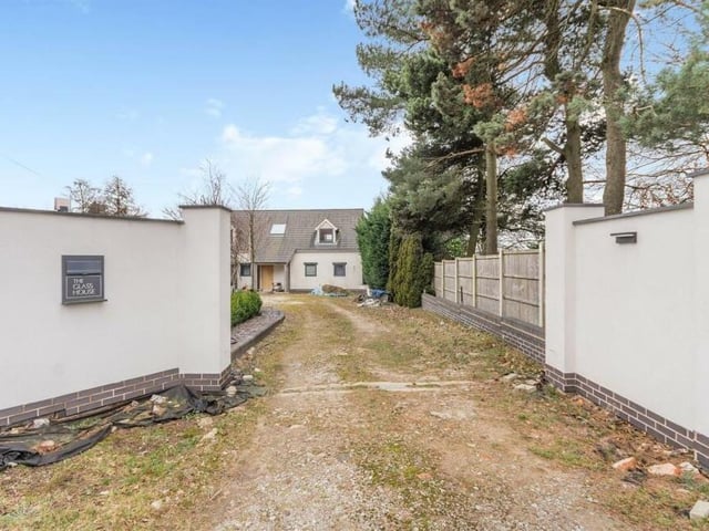 The property is set well back from the road, behind a part-walled frontage that leads to a driveway, providing lots of off-street parking space
