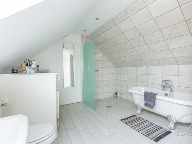 The bathroom on the second floor includes a free-standing bath, enclosed shower, low-flush WC, wash hand basin and cupboard for additional storage.