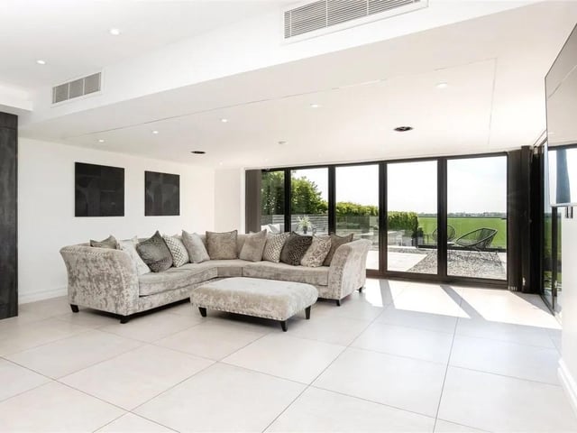 The spacious dining room and informal lounge area is flooded with natural light through floor-to-ceiling windows and bifold doors overlooking the countryside views.