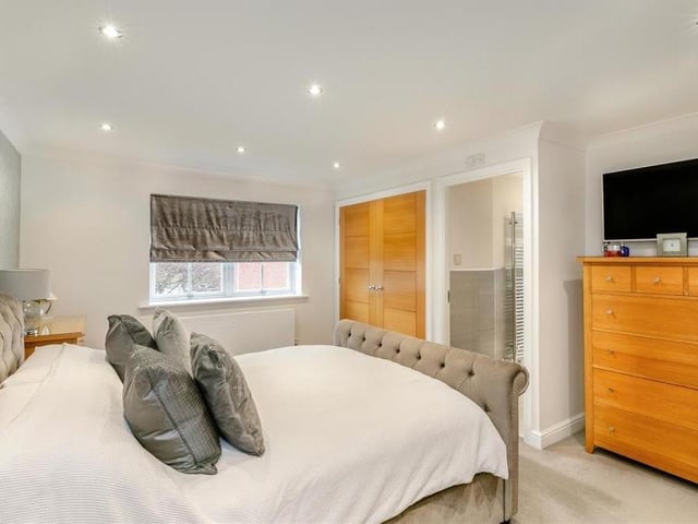 A second shot of the master bedroom shows fitted wardrobes, with hanging rails and shelves, nine ceiling spotlights and access to an en suite bathroom.
