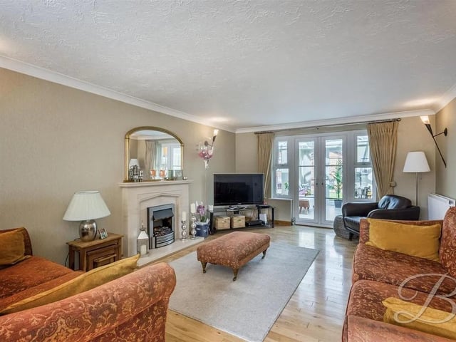 The warm and welcoming living room Includes a feature fire and laminate flooring with a bay window to the front elevation and french doors leading into the garden room.