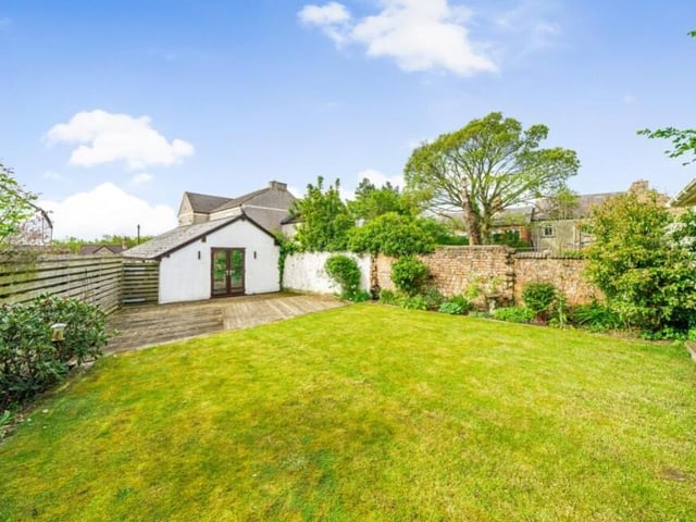 The private, landscaped garden features a large, well-maintained lawn, decking area, storage shed and mature plants and shrubs.