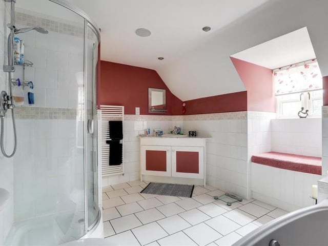 This is the bathroom on the second floor. It consists of a corner fitted shower enclosure with a mains-fed shower, low-flush WC, a vanity unit wash basin and a heated towel-rail. The floor is tiled.