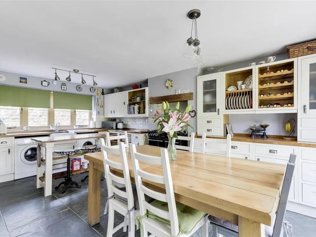 The farmhouse-style kitchen is fitted with a range of country-style units, a breakfast bar for casual dining, and ample space for cooking and entertaining.