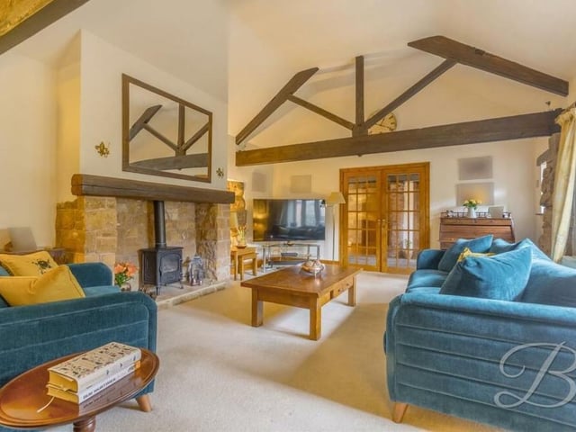 The spectacular living room also includes a feature fireplace, comprising a stove-effect gas fire with beamed mantelpiece.