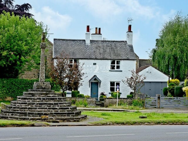 A picture postcard scene as Cosy Cottage sits serenely behind Linby's most famous monument, 'Top Cross', which dates back to the 14th century