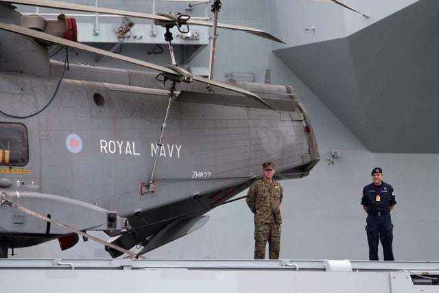 A Royal Navy officer and a member of the US Marines stand next to a Merlin helicopter on the flight deck of HMS Queen Elizabeth. Picture: Andrew Matthews/PA Wire