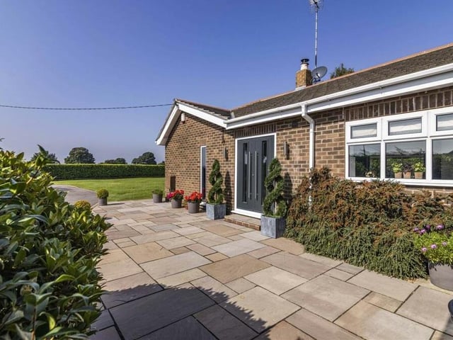 To the side of the property is the welcoming entrance area, with patio and front door.