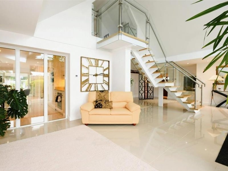 A third shot of the reception hall, which has floor-to-ceiling windows facing the front of the property. There is also a cloaks cupboard, as well as underfloor heating.