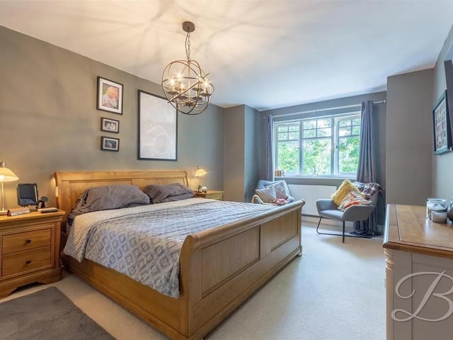 This bedroom features carpeted flooring, a central heating radiator, and a window to the rear elevation. It benefits from a spacious walk-in wardrobe and a private en-suite bathroom.