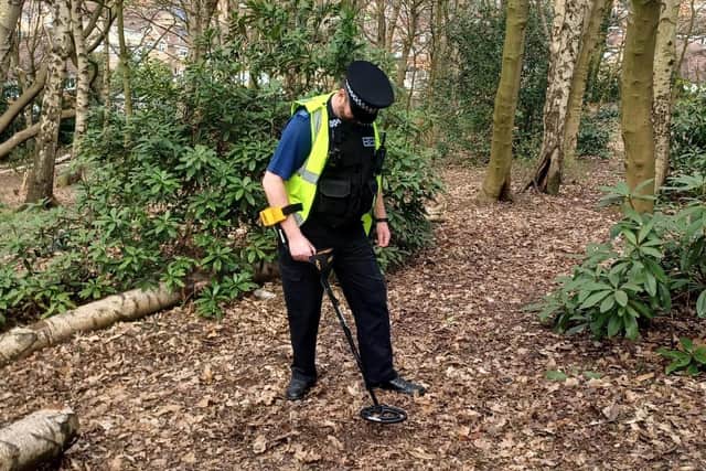 A police community support officer conducts a weapons sweep with a metal detector.