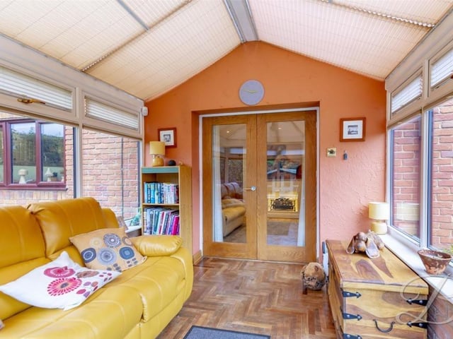 Through the French doors of the snug and into this comfortable conservatory. The room is distinguished by its parquet flooring, surrounding windows and door to the garden.