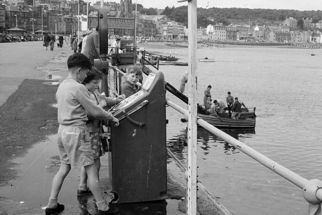 Children playing on an amusement machine on the waterfront at Rothesay, Bute