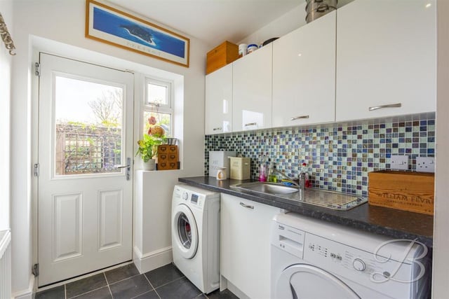 Complete with a range of modern gloss units and cabinets with inset sink and drainer. With space and plumbing for a washing machine and tumble dryer and there is a door leading outside.