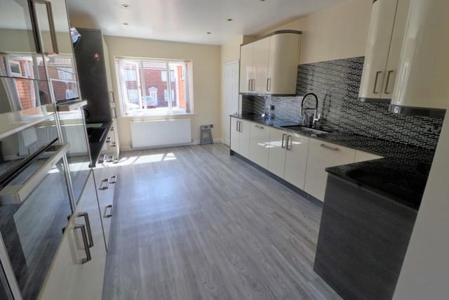 The kitchen also features a host of built-in appliances, including a larder fridge, induction hob, double oven with grills, and integrated microwave. The floor is tiled.