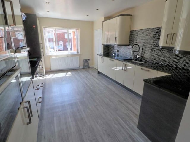 The kitchen also features a host of built-in appliances, including a larder fridge, induction hob, double oven with grills, and integrated microwave. The floor is tiled.