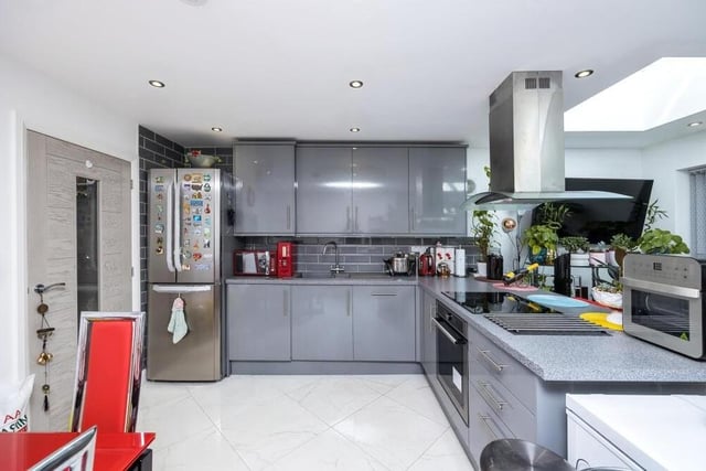 Much of the ground floor is open plan, including this modern kitchen, which features a range of high-gloss wall and base units, with integrated appliances and a breakfast bar.