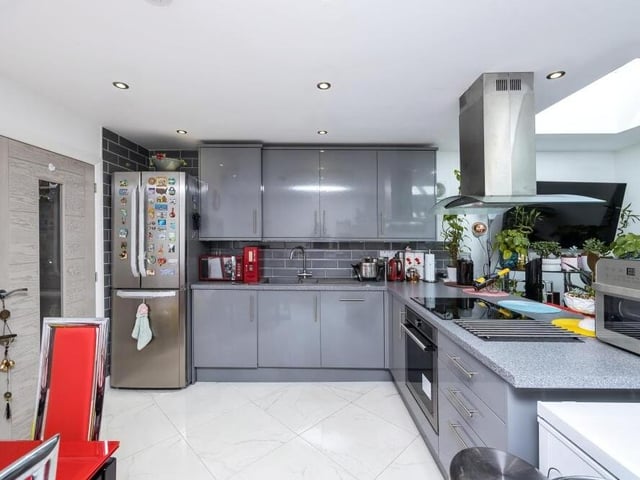 Much of the ground floor is open plan, including this modern kitchen, which features a range of high-gloss wall and base units, with integrated appliances and a breakfast bar.