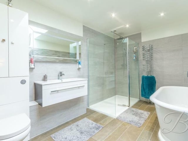 The main bedroom also has access to this en suite bathroom, complete with a free-standing bath and spacious, enclosed shower. There is also a wall-hung wash basin, low-flush WC, vanity storage, two chrome, heated towel-rails, a tiled floor, full-height wall-tiling and a skylight.